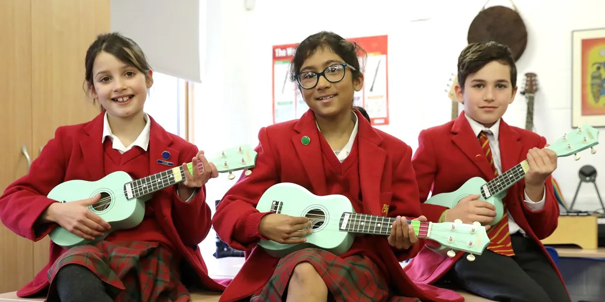 three female students playing ukulele